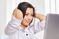 Close up portrait of a young businesswoman looking at her laptop, relaxed and smiling.