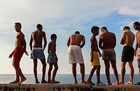 Kids in their bathing suits standing along the seawall about to go swimming along the Malecón (Avenida de Maceo) in Central Havana, Cuba.