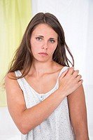 Young woman holding her painful shoulder suffering from rheumatism