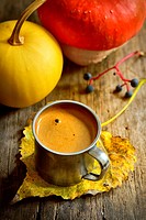 Autumn cup of coffee and pumpkin on wooden background.