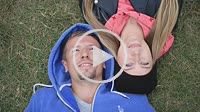 Sweethearts students lying on grass head to head