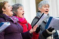 A group of women singing christmas carols on the main street in Aberystwyth collecting to raise money for charity, Wales UK.