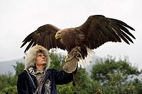 Trainer holding a White Tailed Eagle up with spread wings at Sunkar Falcon Farm Almaty Kazakhstan.