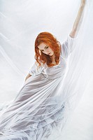 Redhair maiden in white tissut in abstact surroundings.