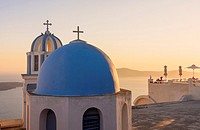 Sunset over a blue domed church and balcony on Santorini Island, Cyclades, Greece.