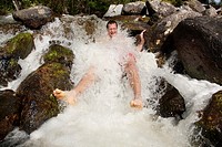 Man sitting in a rushing stream, countryside of northern Sweden.