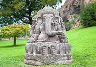 Ganesha statue, made of stone, with a beautiful mountain garden in background.