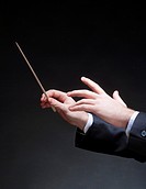 Hands of Conductor with Baton Leading Orchestra.