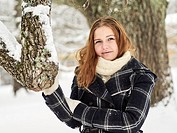 Beautiful young girl wearing a winter coat and she looks toward a camera, Finnish winter day on February.