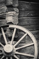 Old wagon wheel outside rural building wall. Rustic wooden nostalgia object.