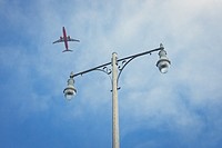 Commercial airliner taking off from San Diego International Airport with lamp post and blue sky in the background