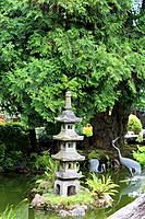 A landscaped Japanese garden with a Japanese stone lantern and bird statues in a pond in California, USA.