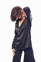 Young dark-haired girl in stylish clothes posing in front of camera. The girl is very cute and has a model appearance and a good slender figure. Cloth...