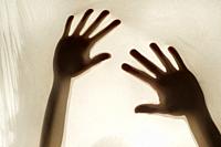 Photographic representation of violence on women, hands against sheet.