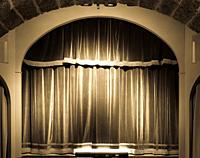 A red curtain in an old and very small Italian theatre.