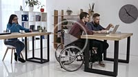 Hipster man in wheelchair working in office