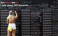 Woman taking a photo of a Wall with statements about HIV awareness, ""Start taking. Stop HIV. I talk about HIV because . . . "" during Charlotte Pride...