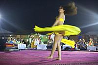 Belly dancer performing a traditional dance in the open air at night, near Abu Dhabi, United Arab Emirates, Middle East.