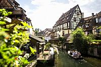 Tourists boat along channel at Little Venice in medieval town of Colmar, Alsace (department of Haut-Rhin, region of Grand Est, France).