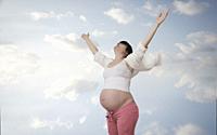 Pregnant woman lifting arms to sky