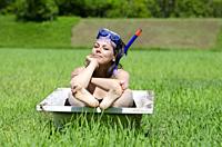 Woman with Diving Mask Sitting in a Bathtub on a Green Field with Grass in Locarno, Switzerland.