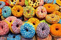 Rotterdam, Netherlands. Stack of very colorful donuts for sale on a Market Hall market stand down town. Creativity when making donuts is booming, espe...