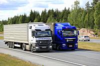 Blue MAN semi truck overtakes another truck on motorway in summer. Trucks with heavy cargo can be much slower uphill. Salo, Finland - June 8, 2018.