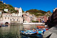 Fishing boats in harbour and tourists on the little beach, Vernazza, Italian Riviera, Liguria, Italy.