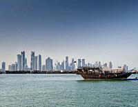 doha city skyscrapers urban skyline view and dhow boat in qatar.