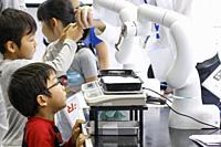 October 21, 2018, Tokyo, Japan - Children look at a robot arm developed by DENSO Corp. performing during the World Robot Summit 2018 at Tokyo Big Sigh...