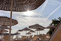 Sunshades and sun lounger at the beach with noone, low season in the morning. South of Bodrum, Turkey.