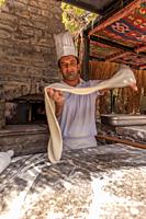 Turkish pide baker baking pide for tourists at an outdoor kitchen at the beach. Near Bodrum, Turkish Riviera,Turkey,Eurasia,.
