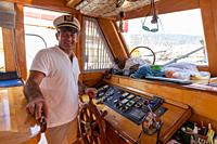 Captain at steering wheel on yacht/sailboat while boat is in harbour. Bodrum, Turkey.
