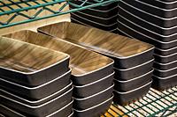Stacks of rectangle ceramic food containers on a green metal wire rack.