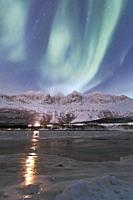 The Northern Lights and starry sky reflected in the frozen sea Nordkjosbotn Lyngen Alps Tromsø Norway Europe.