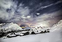 Starry sky above the alpine village of Grevasalvas covered with snow, Maloja, canton of Graubunden, Engadin, Switzerland.