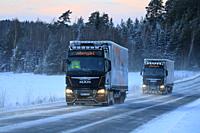 Salo, Finland - January 18, 2019: Two Customised MAN semi trailer trucks of Stengel LT haul goods through winter scenery at dusk in South of Finland.