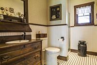 Guest bathroom with antique wooden dresser sink cabinet, toilet, old milk collecting pail inside a LEED certified Country home