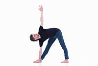 Casual dressed young adult man making yoga exercises on white background.