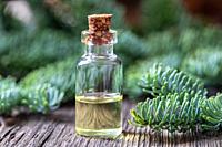A bottle of essential oil with fir branches.