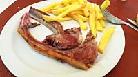 Two crispy lamb chops with fried potatoes. Mediterranean culinary delicacy