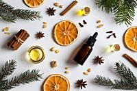 Selection of essential oils with Christmas spices and ingredients on white background: bottles of essential oil, spruce, fir, frankincense resin, star...