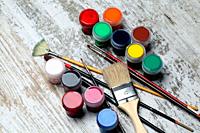 Brushes and artistic paint of different colors on artistic background