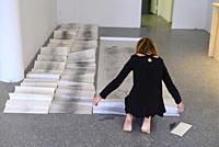 A woman artist aged 50 to 55 years old creates performance art that incorporates drawing, text, and walking.