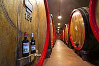 Bottles of liquor Amaro Braulio and oak barrels in the cellar, Bormio, Sondrio province, Valtellina, Lombardy, Italy.