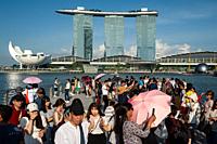 Singapore, Republic of Singapore, Asia - Tourists visit Merlion Park along the Singapore River with the Marina Bay Sands Hotel in the backdrop.
