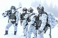 Winter arctic mountains warfare. Action in cold conditions. Squad of soldiers with weapons in forest somewhere above the Arctic Circle.