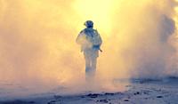 Special operations forces soldier, army ranger or commando in camo uniform, helmet and ballistic glasses walking at battlefield covered with smoke. Ai...