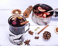 mulled wine in a glass with an iron cup holder on a white wooden background, top view.  