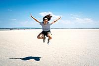 Full-length portrait of joyful female traveler jumping on the beach in the bay of Mont Saint-Michel.
